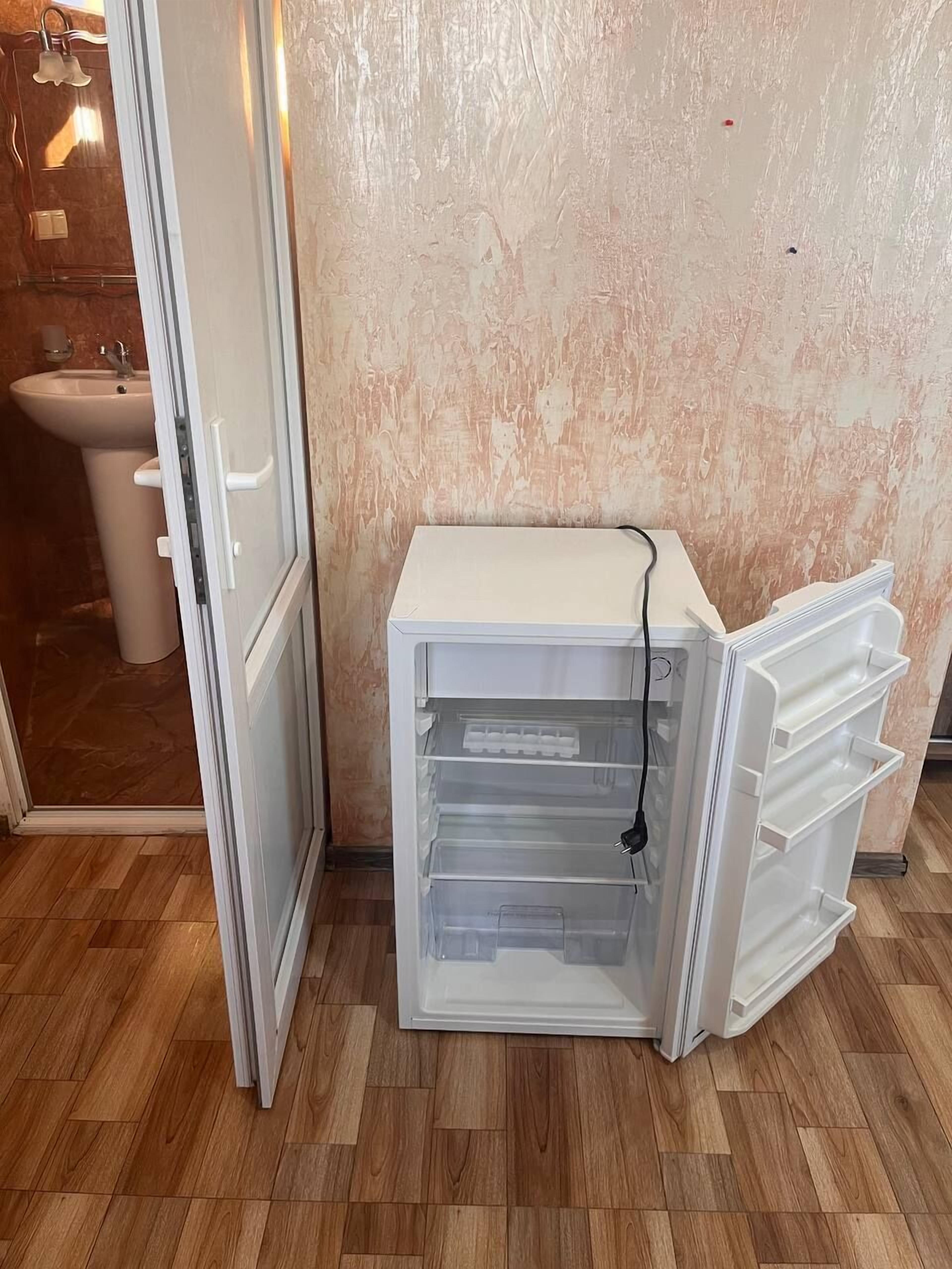 Eine kleine Küche mit integriertem Kühlschrank, Spüle und Dusche.