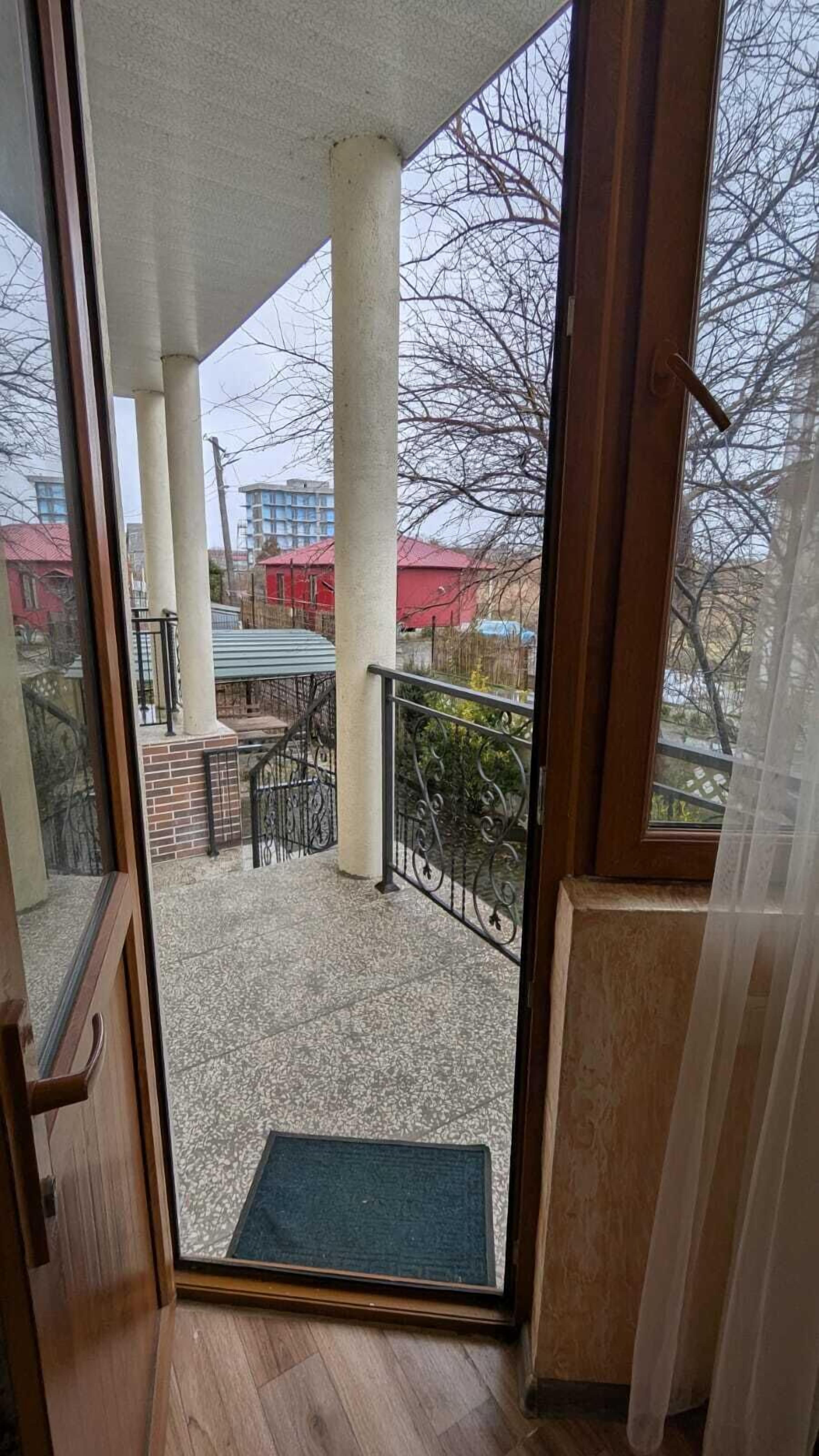 A view from a balcony with a wooden floor, a metal railing, and a clear sky.