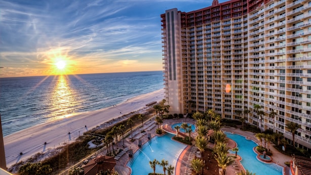 A high-rise hotel with a pool area, beachfront view, and multiple balconies. - Amazing Gulf Views! Spa, Pool, Tiki Bar and More! (Panama City Beach)