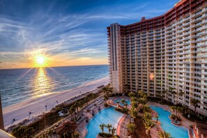 Un hôtel de grande hauteur doté d’une piscine, offrant une vue sur la plage et comprenant plusieurs balcons.