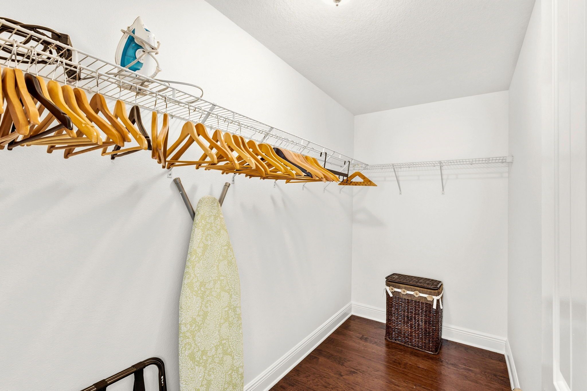 A room with a clothes drying rack, a basket, and a small table.