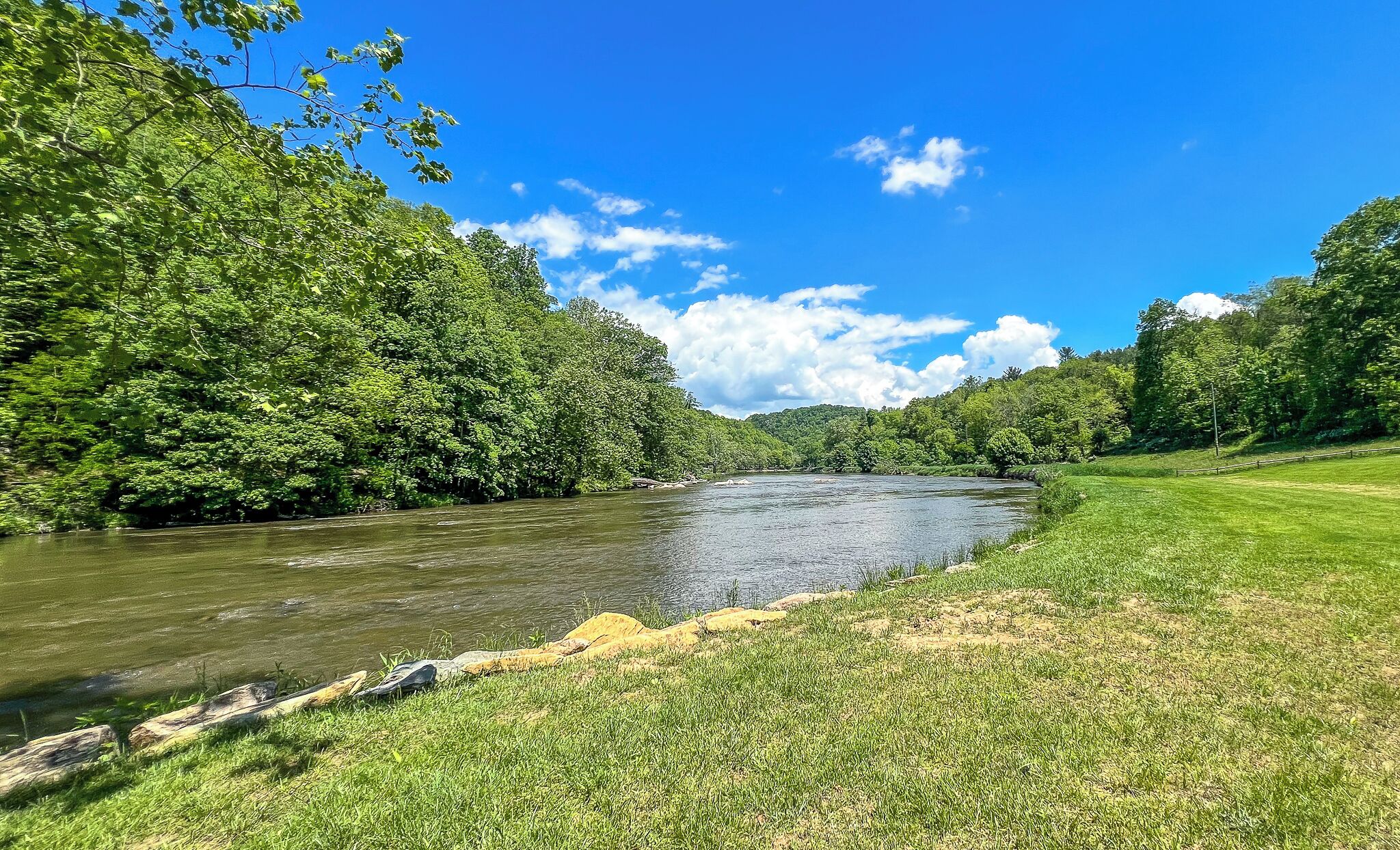 A river flowing through a lush green landscape with dense trees on both sides.