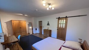 A bedroom with a bed, a desk, a chair, a wardrobe, and a door. - The Property (Rentweinsdorf)