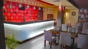 A hotel lobby with a reception desk, seating area, and decorative wall art. - Kings Resort (Gobindpur)