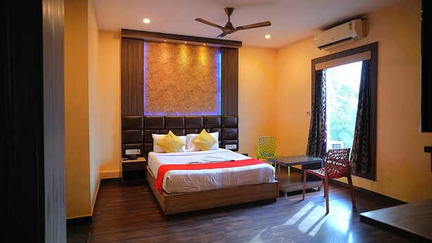 A modern hotel room with a large bed, a ceiling fan, an air conditioning unit, and a view of the outdoors. - Kings Resort (Gobindpur)