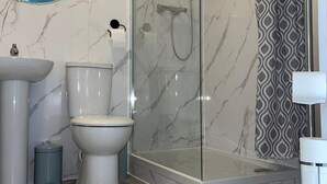 A modern bathroom with a glass-enclosed shower, a toilet, and a sink. - Crescent Apartment - Two bedroom (Romford)