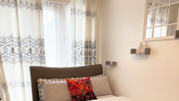 A neatly made bed with a fluffy blue rug, a headboard, and decorative pillows. - Crescent Apartment - Two bedroom (Romford)