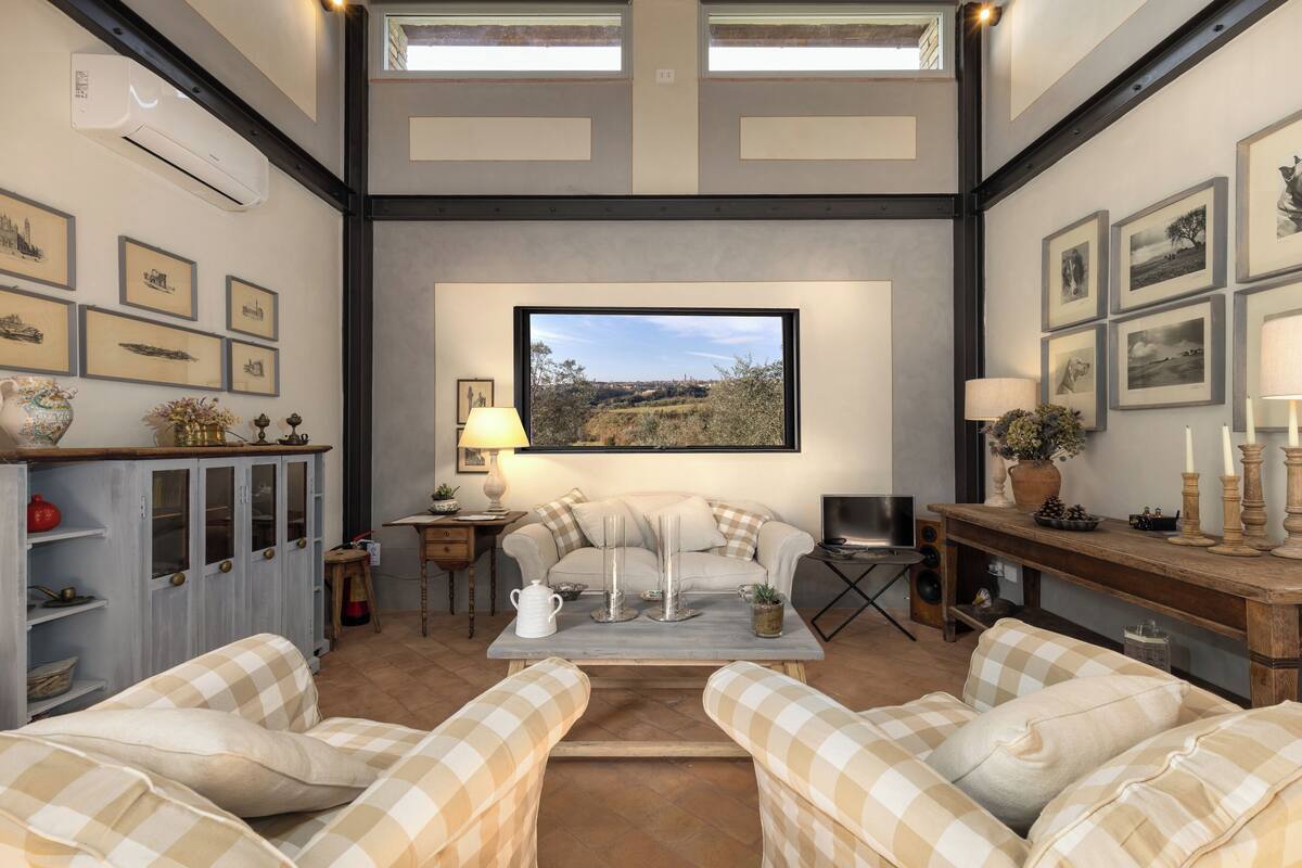 Un salón acogedor con un ventanal grande, un sofá, una mesa de centro y un televisor.