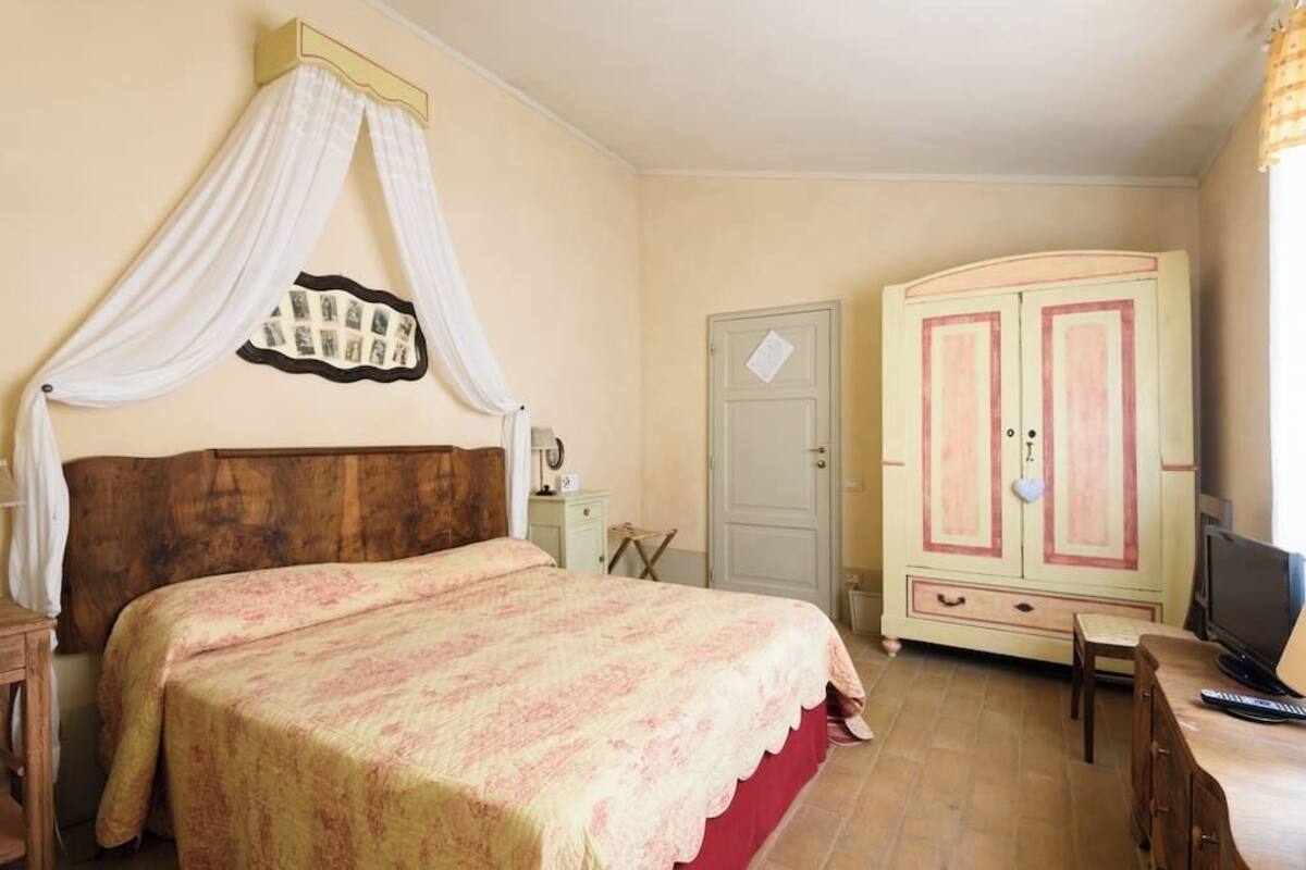 Un dormitorio con cama, armario, televisión y escritorio.