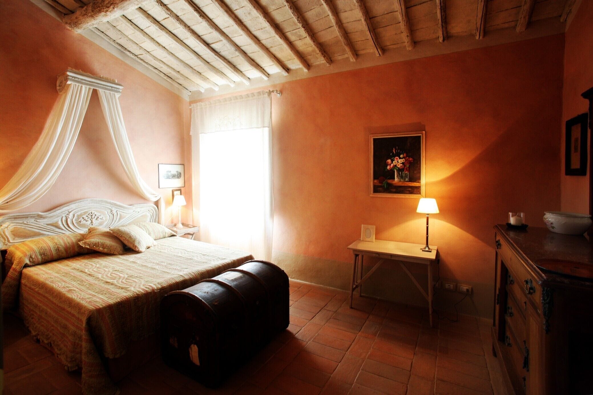 Une chambre à coucher avec un lit, une table de chevet, une lampe, un tableau et une commode en bois.