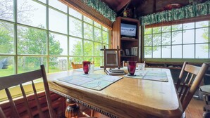 Una mesa de madera para comer con dos sillas, una estantería y un televisor.