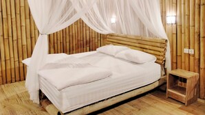 Una cama con sábanas blancas, cabecera de madera y una pequeña mesita de noche a su lado.