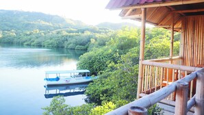 Una estructura de madera con techo rojo que domina un lago tranquilo y abundante vegetación.