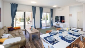 Un salon moderne avec un canapé, une table à manger pour quatre personnes et un ventilateur de plafond.