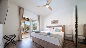 Une chambre avec un grand lit, un ventilateur de plafond et une vue sur l’extérieur.