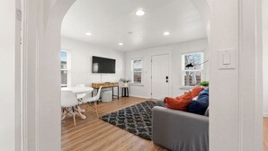 Un espace de vie à aire ouverte comprenant une table à manger, un canapé et un téléviseur fixé au mur.
