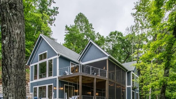 Une maison à deux étages avec une terrasse en bois donnant sur un porche abrité.