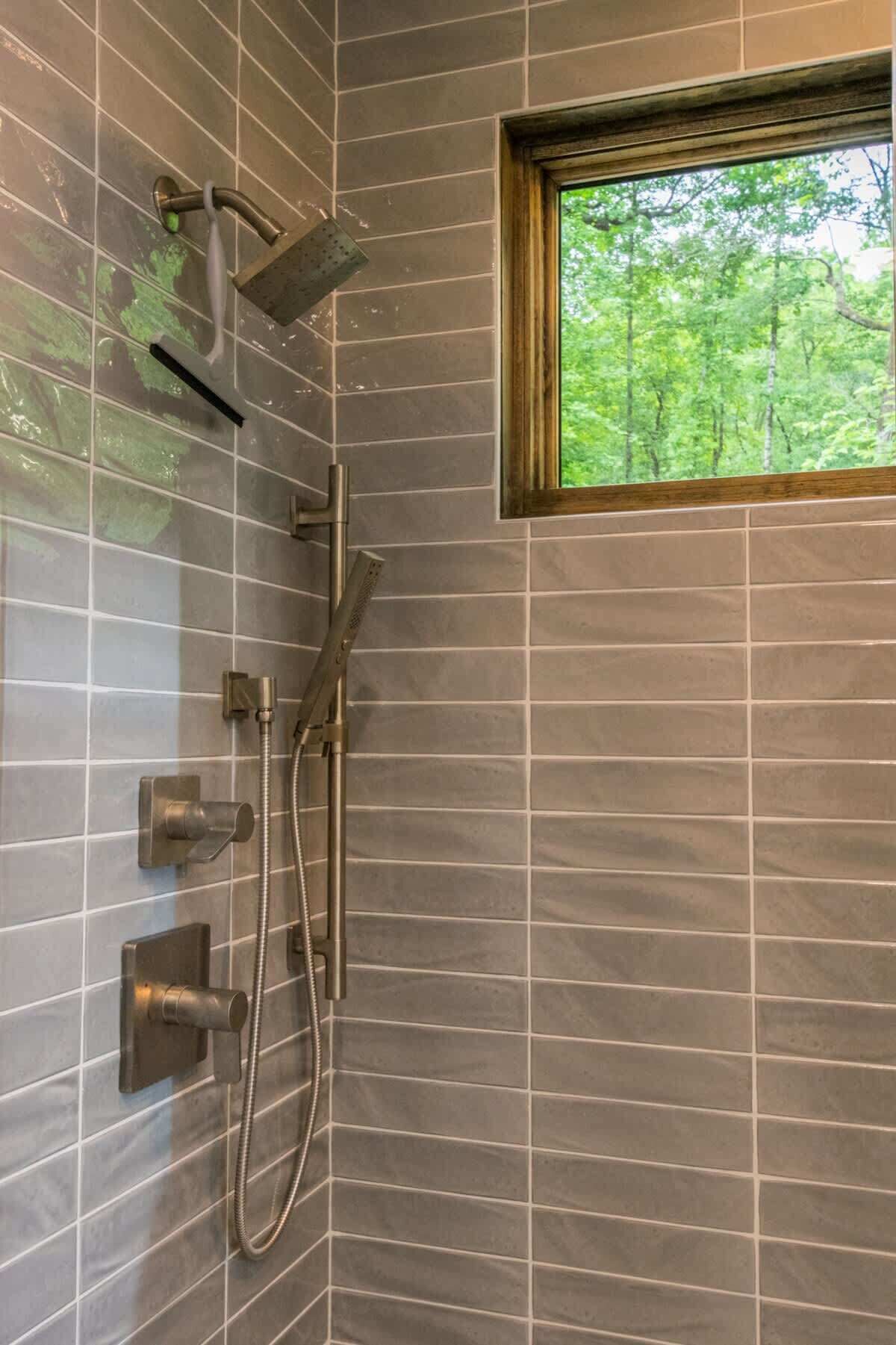 Une douche équipée d’un pommeau de douche à effet pluie, d’un pommeau de douche à main et d’un flexible de douche à main.