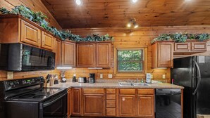 Une cuisine avec des meubles de rangement en bois, un réfrigérateur noir, un four à micro-ondes et un lave-vaisselle.