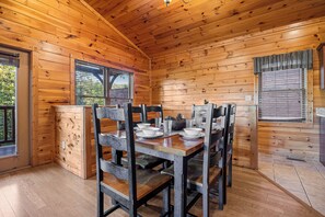A wooden cabin with a dining table set for four, surrounded by chairs. - Views, Hot Tub, Fireplace, Resort Pool, + Game Room (Gatlinburg)