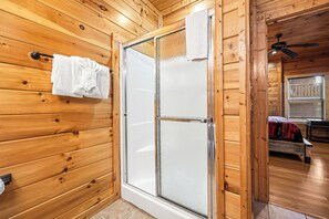 A wooden cabin bathroom with a glass shower door, a towel rack, and a ceiling fan. - Views, Hot Tub, Fireplace, Resort Pool, + Game Room (Gatlinburg)