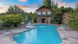 A swimming pool with lounge chairs, a lifeguard stand, and a stone building in the background. - Views, Hot Tub, Fireplace, Resort Pool, + Game Room (Gatlinburg)