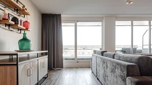 Una sala moderna con sofá, un aparador de madera y un ventanal con vista a la ciudad.