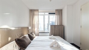 Una habitación de hotel con una cama grande, un armario y una ventana con cortinas.