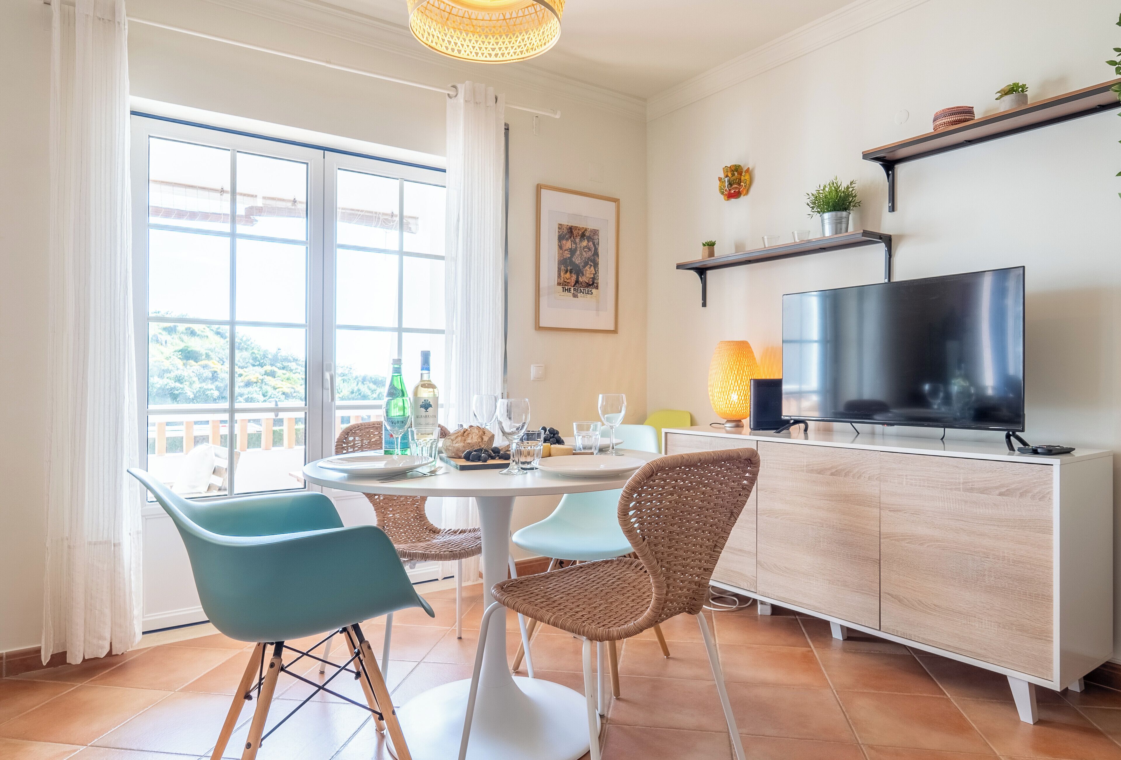 A dining area with a round table, chairs, and a TV on a cabinet.