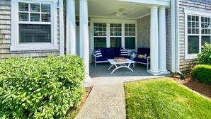 A two-story house with a covered porch, a blue sofa, and a small table.