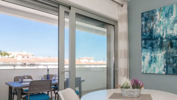 A modern room with a balcony, a round table with chairs, and a painting on the wall. - Coastal Haven apartment Lagos (Lagos)