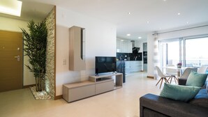 A modern living room with a TV, sofa, and dining area. - Coastal Haven apartment Lagos (Lagos)