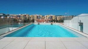 A rooftop swimming pool with clear blue water, surrounded by modern buildings and a clear sky. - Coastal Haven apartment Lagos (Lagos)