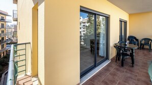 A balcony with a sliding glass door, a table with chairs, and a view of the cityscape. - Apartment Lesley - great location! (Armação de Pêra)