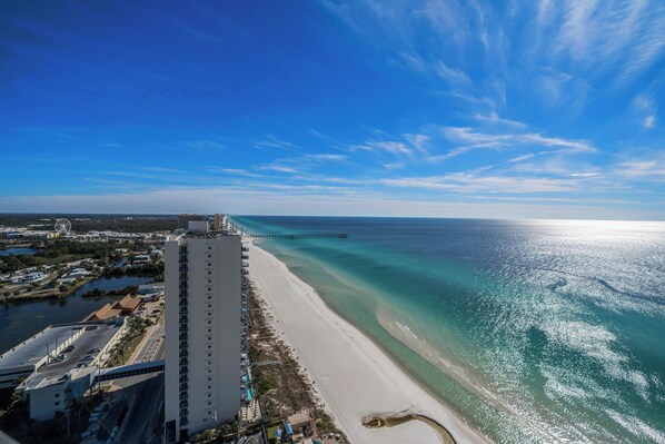A high-rise hotel with a beach view, a pier, and a clear blue sky. - Breathtaking Views from this 30th floor 1BR + Bunks Condo at the Tidewater. (Panama City Beach)