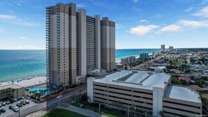 Un hotel de gran altura con varios pisos, un estacionamiento y vistas a la playa y al océano.