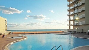 Una piscina con vista a la playa y un edificio con balcones.