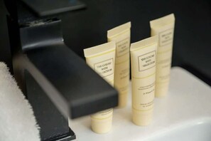 A row of cream-colored bath products labeled "The Luxury Bath Collection" on a white surface.