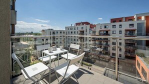 A rooftop terrace with outdoor seating and a view of adjacent buildings.