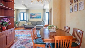 A dining area with a wooden table, chairs, and a chandelier. - Elegante Appartamento con Spiaggia sul Mare di Bari (Bari)