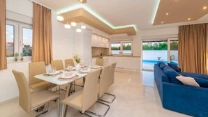 Una sala de estar moderna con comedor, un sofá azul y una cocina al fondo.
