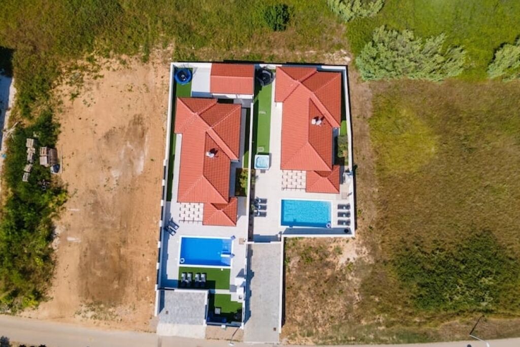 Vue aérienne d’une propriété dotée d’une piscine, d’un court de tennis et d’un patio couvert.