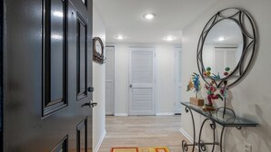 A hallway with a black door, white walls, and a mirror on the right. - ~ Beach Breeze ~   Beautiful Oceanfront 3 Bed/2 Bath Condo (Myrtle Beach)