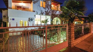 A two-story house with a balcony, a gated entrance, and a well-lit interior.