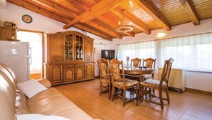 A cozy living room with a wooden ceiling, a dining area with a table and chairs, and a built-in wooden cabinet.