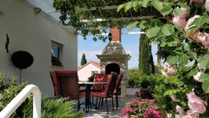 An outdoor patio with a table and chairs, a brick oven, and potted plants. - Villa Mediterranea (Zupa dubrovacka)