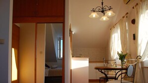 A compact living space with a dining area, kitchenette, and a bedroom with a sloped ceiling. - Villa Mediterranea (Zupa dubrovacka)