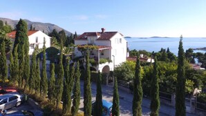 A coastal property with a white building, red-tiled roof, and a view of the sea. - Villa Mediterranea (Zupa dubrovacka)