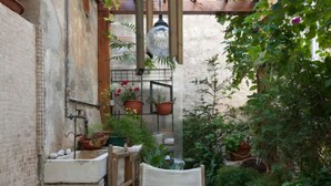 A small, enclosed patio with a table and chairs, surrounded by potted plants and a hanging light fixture. - Apartment Ivančica (Dubrovnik)