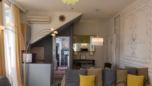 A modern hotel room with a sofa, a dining area, and a staircase leading to an upper level. - Apartment Ivančica (Dubrovnik)